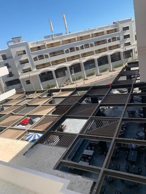 A multi-story hotel with a rooftop terrace featuring outdoor seating and a view of a white building with minarets. - La prestigia Hurghada Apartment (Red Sea Governorate)