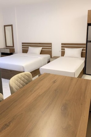 Habitación de hotel con dos camas, una mesa de madera y una silla.