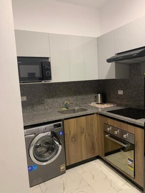 Cocina compacta con lavadora, horno, microondas y pileta.