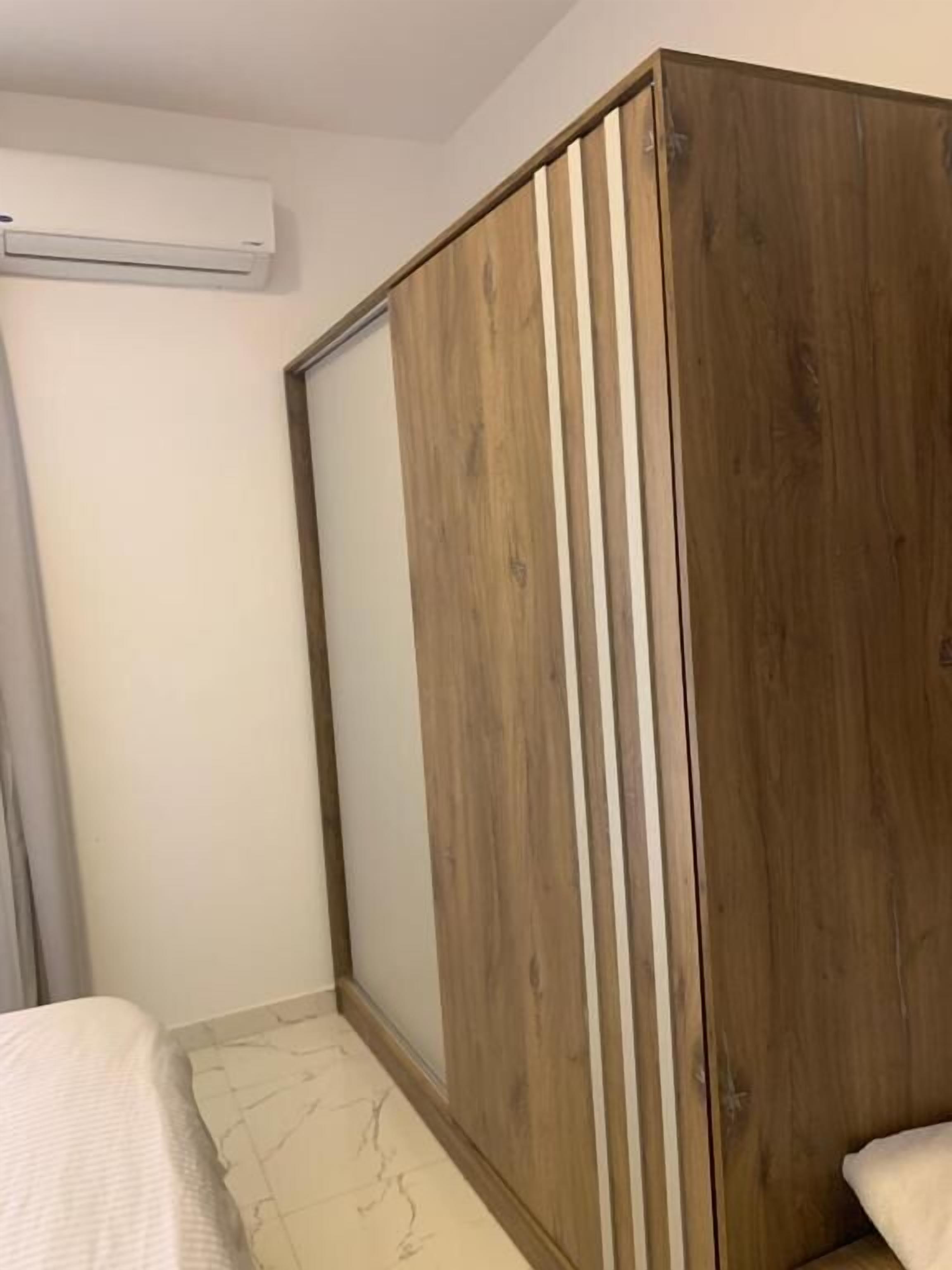 A bedroom with a bed, a wardrobe, and an air conditioning unit.