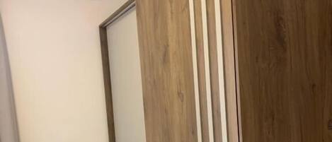 A bedroom with a bed, a wardrobe, and an air conditioning unit.