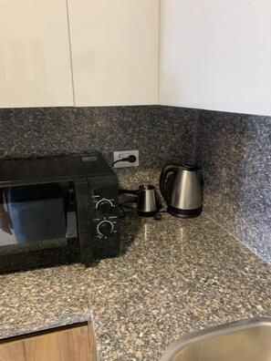A kitchen with a microwave, a kettle, and a coffee maker on a granite countertop. - La prestigia Hurghada Apartment (Red Sea Governorate)