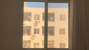 A room with a large window, a blue sofa, and a white chair. - La prestigia Hurghada Apartment (Red Sea Governorate)