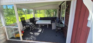A covered patio area with a sofa, a table, and chairs.