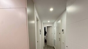 A narrow hallway with wooden flooring and white walls, leading to a room with a door at the end. - Playa del Cura Spa Retreat (Torrevieja)