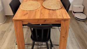 A wooden dining table with woven placemats, black chairs, and a decorative painting above. - Playa del Cura Spa Retreat (Torrevieja)