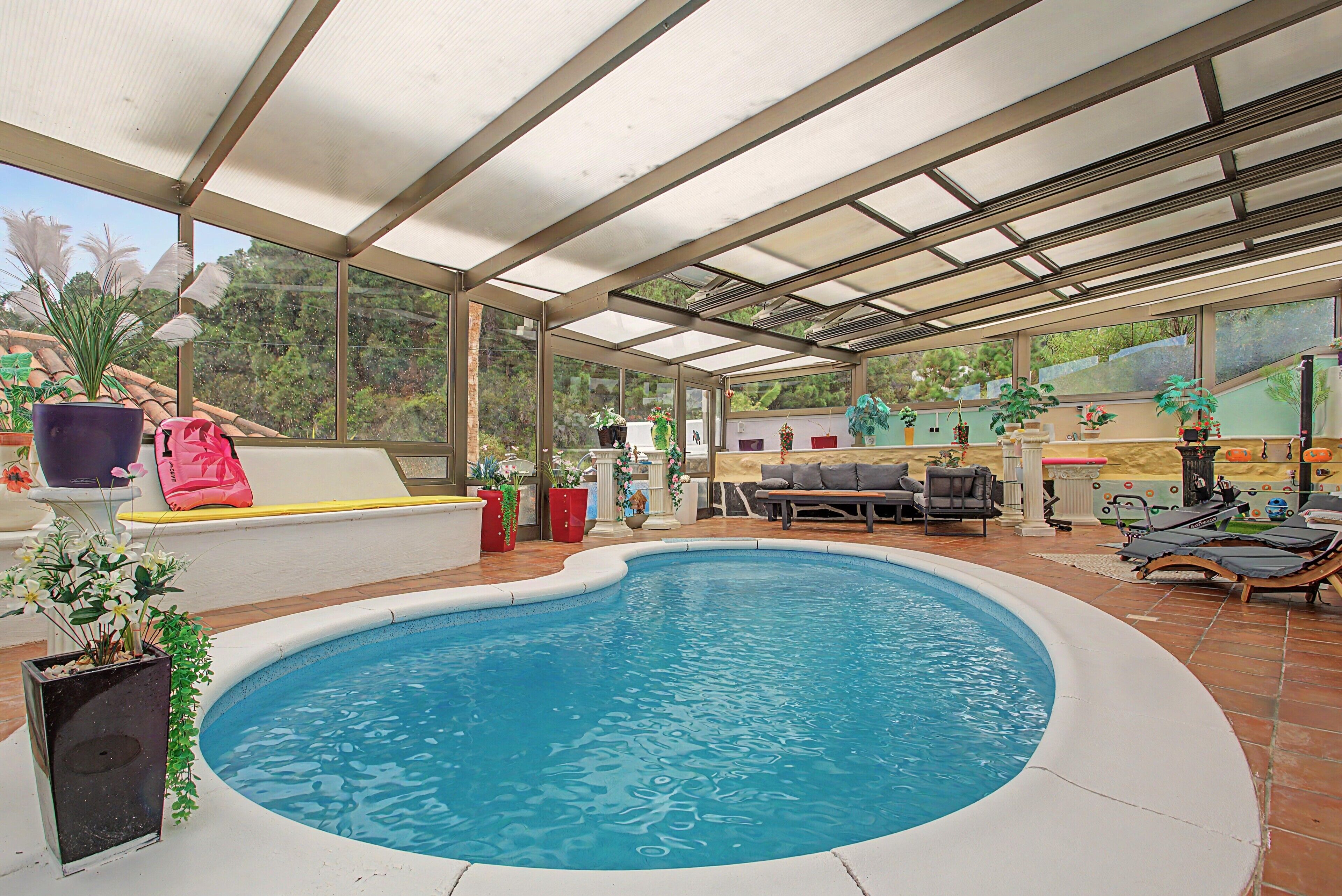 Piscina techada al aire libre con zona de estar y sillones reclinables.