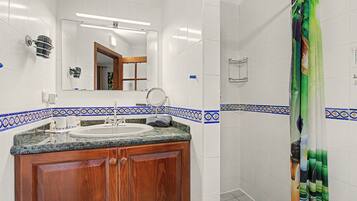 Une salle de bain avec un lavabo, un miroir et un rideau de douche.