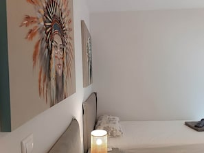 A bedroom with a bed, a wall-mounted lamp, and a painting. - Sea la  Vie (Saronida)