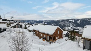 Un pueblo nevado con casas de madera, un telesilla y una montaña al fondo.