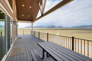 A covered outdoor deck with a bench, overlooking a vast open landscape with distant mountains. - Mtn-View Deck! Remote South Park Retreat (Hartsel)