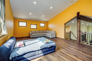 A room with a sofa, a window, a wooden floor, and a staircase. - Mtn-View Deck! Remote South Park Retreat (Hartsel)