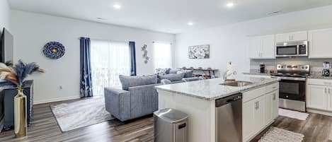 A modern kitchen with white cabinets, a stainless steel dishwasher, and a built-in oven.