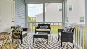 A covered porch with wicker furniture, a patterned rug, and a view of a residential area. - 2 Townhome Retreat | Sleeps 12 | 40 Min to Raleigh (Wilson)