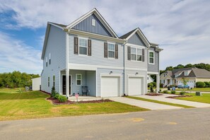 A two-story residential house with a garage, a front porch, and a well-maintained lawn. - 2 Townhome Retreat | Sleeps 12 | 40 Min to Raleigh (Wilson)