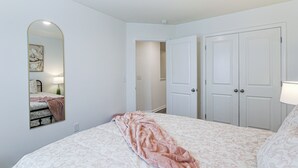 A bedroom with a bed, a mirror, a wardrobe, and a door leading to another room. - 2 Townhome Retreat | Sleeps 12 | 40 Min to Raleigh (Wilson)