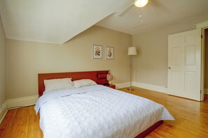 A bedroom with a bed, a nightstand, a lamp, and a door. - Twin Cities Duplex Near Downtown Minneapolis (Saint Paul)