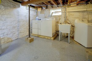 A laundry room with two washing machines, a utility sink, and a water heater. - Twin Cities Duplex Near Downtown Minneapolis (Saint Paul)