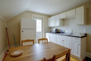 A kitchen with white cabinets, a refrigerator, a sink, and a dining table with chairs. - Twin Cities Duplex Near Downtown Minneapolis (Saint Paul)