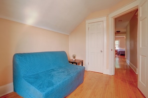 A room with a blue sofa, a small table with a plant, and a door leading to another room. - Twin Cities Duplex Near Downtown Minneapolis (Saint Paul)