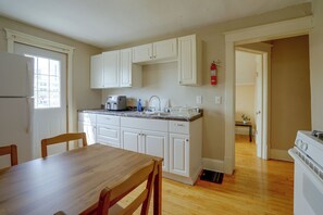 A compact kitchen with white cabinets, a built-in oven, and a dining area with a wooden table and chairs. - Twin Cities Duplex Near Downtown Minneapolis (Saint Paul)