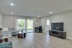 Ein modernes Wohnzimmer mit Sofa, Couchtisch, Fernseher und einer Schiebetür zu einer Terrasse.