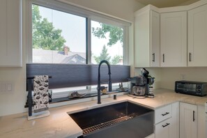 A kitchen with a large window, a sink, a coffee maker, and a toaster. - 1 Mi to UM Campus! Newly Built Apt w/ Side Yard (Missoula)