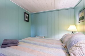 A room with a bed, a lamp, and a picture on the wall.