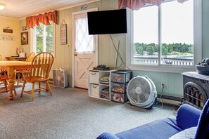 A cozy room with a dining table, chairs, a television, and a view of a lake.