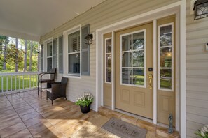 A covered porch with a bench and a welcome mat.