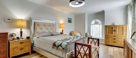Un dormitorio con cama, mesitas de noche, una silla, armario y ventilador de techo.