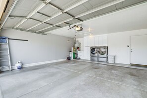 Eine Garage mit Betonboden, Warmwasserbereiter, Waschmaschine und einer Leiter.