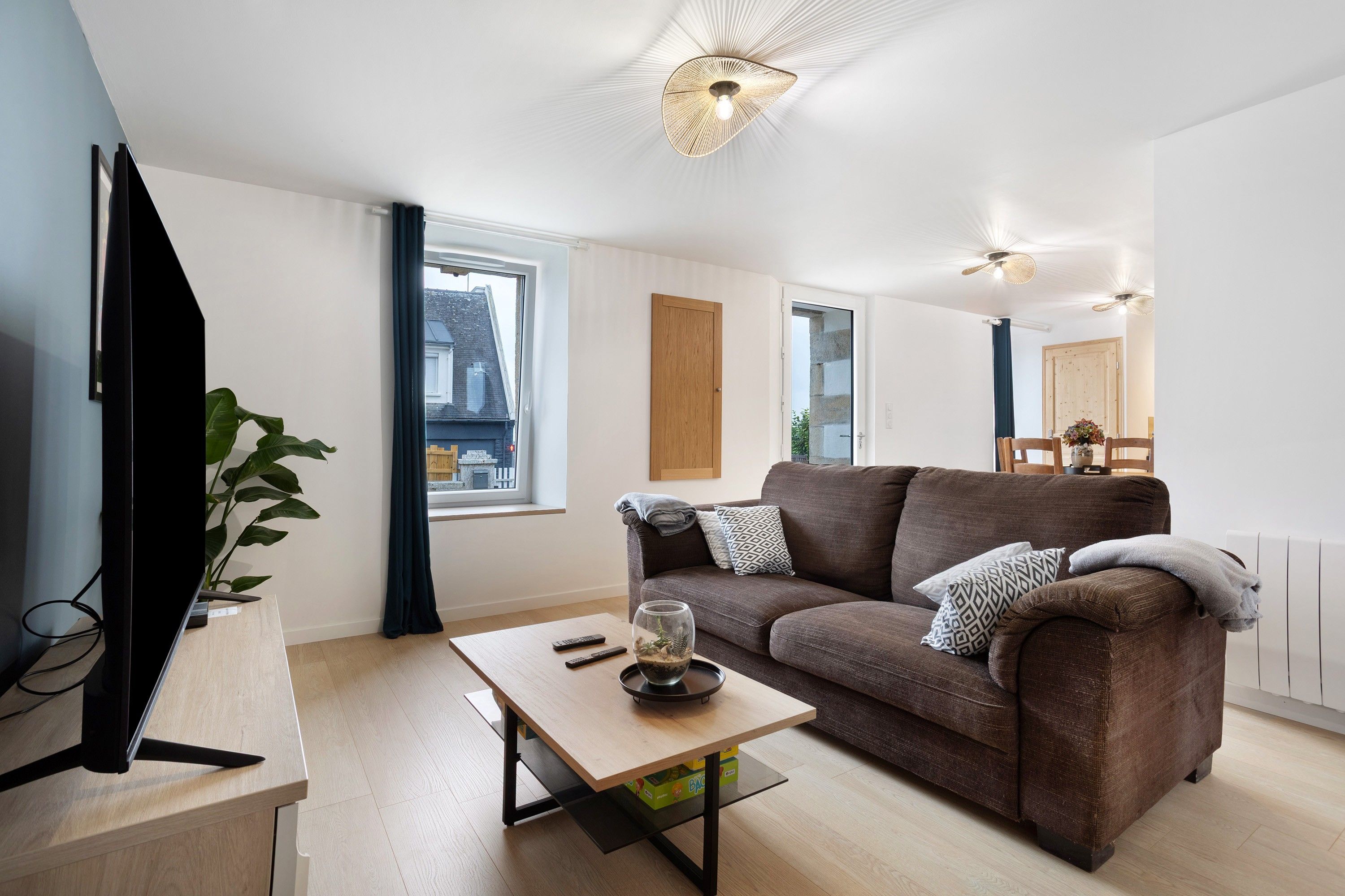 Un salon moderne avec un canapé, une table basse, un téléviseur et une grande fenêtre.
