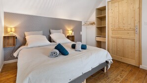 Un dormitorio con una cama, dos mesitas de noche, un armario de madera y un papel tapiz estampado.