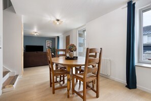 A dining area with a round wooden table, four chairs, and a vase with flowers.