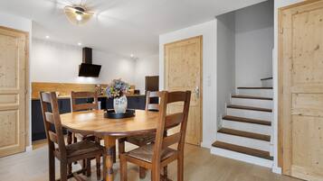 Un coin repas avec une table ronde, des chaises en bois, un vase de fleurs et un luminaire moderne au plafond.