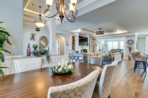 A spacious dining area with a wooden table, upholstered chairs, and a chandelier. - Sun, Fun & Soak: Stunning Myrtle Beach Escape! (Myrtle Beach)