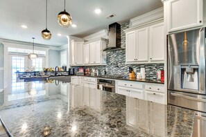 Uma cozinha espaçosa com uma ilha grande, eletrodomésticos de aço inoxidável e uma elegante parede de azulejos.