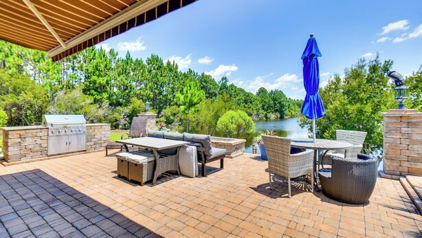 An outdoor patio with a grill, wicker furniture, and a view of a lake. - Sun, Fun & Soak: Stunning Myrtle Beach Escape! (Myrtle Beach)