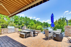 Patio esterno con barbecue, mobili in vimini e vista sul lago.