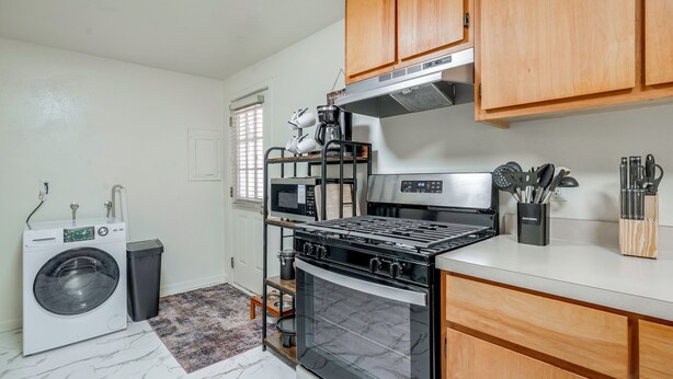 A compact kitchen with a washing machine, oven, microwave, and wooden cabinets. - Walk to Dtwn Corvallis: Home Near OSU & Riverwalk (Corvallis)