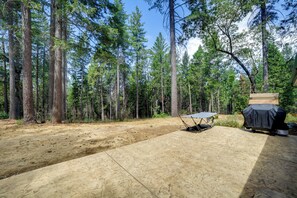 A camping area with a tent, a barbecue grill, and a paved ground surrounded by tall trees. - Horse-Friendly Escape w/ 400 Mi of Trails (Georgetown)