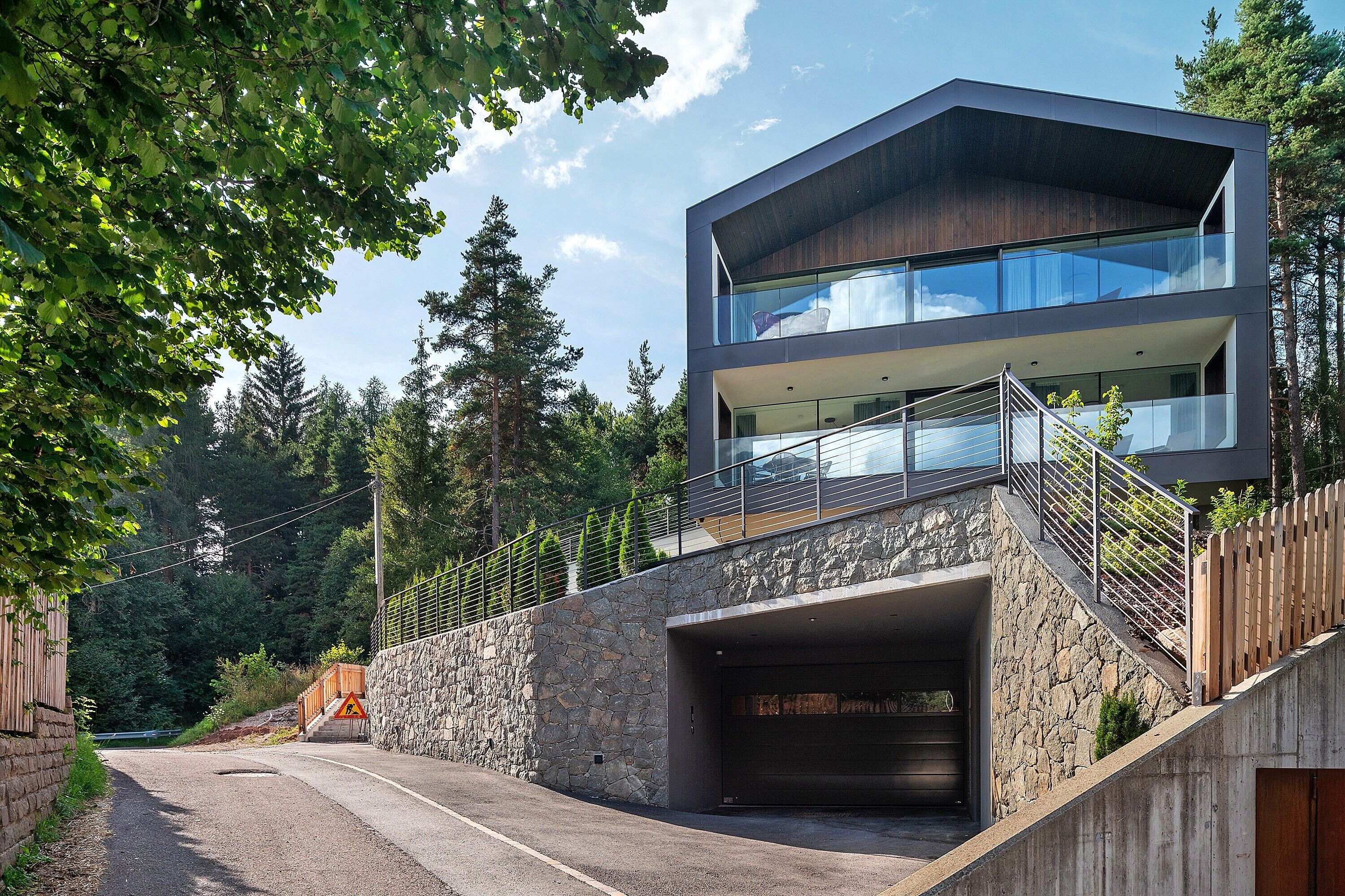 A modern two-story building with a stone facade, a balcony, and a garage entrance.