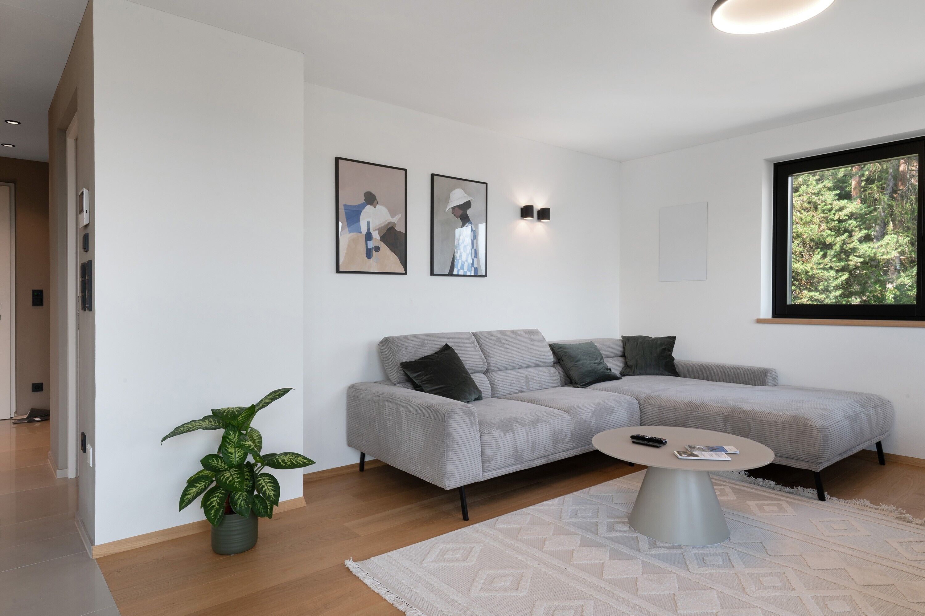 A modern living room with a grey sectional sofa, a small round coffee table, and a potted plant.