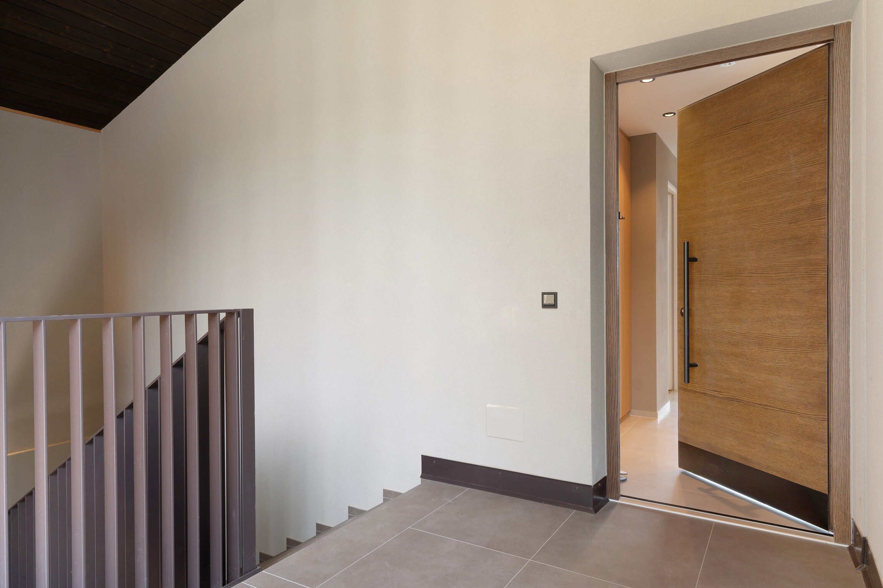 A staircase with a metal railing leading to a wooden door.