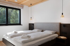 A bedroom with a bed, two bedside tables, a window, and a ceiling light fixture. - Apartment 2nd Floor - Villa Aulank (Ritten)