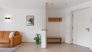 Una sala de estar moderna con un sofá, una mesita, una planta en maceta y un cuadro colgado en la pared.