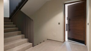 Una escalera de diseño moderno, una puerta de madera y un interruptor de luz en la pared.