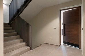 Una escala de disseny modern, una porta de fusta i un interruptor a la paret.