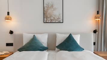 A hotel room with a bed, two pillows, a nightstand, a framed picture on the wall, and two wall-mounted lamps.